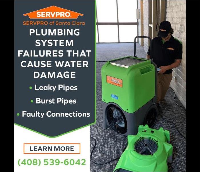 SERVPRO employee using a large green air mover indoors, with sunlight filtering through a window onto a wet floor.